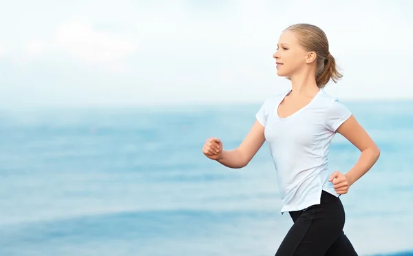 Junge Frau läuft am Strand der Küste des Meeres — Stockfoto