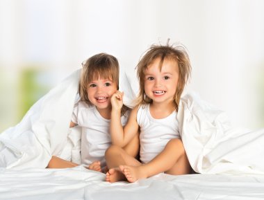 mutlu küçük kızın ikiz kardeşi olan battaniye altında yatakta