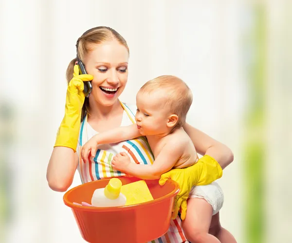 Jonge gelukkig moeder is een huisvrouw met een baby doet huiswerk en — Stockfoto