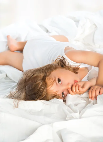 Klein meisje in bed liggen en zuigt een vinger — Stockfoto