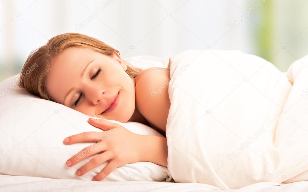 beautiful woman sleeping and smiles in his sleep in bed