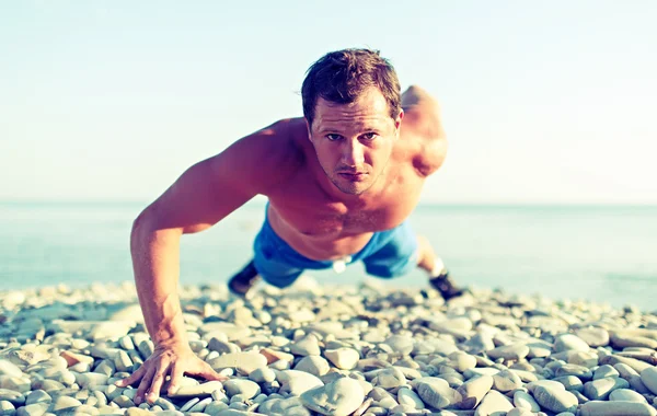 Allenamenti atletici maschili spinti sulla natura sulla spiaggia — Foto Stock