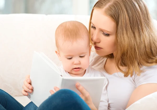 Mère lisant un livre un petit bébé sur le canapé — Photo