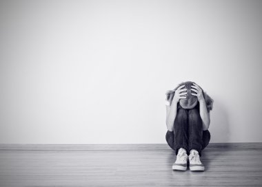 Kız bir depresyon duvarın yanında yerde oturuyor.