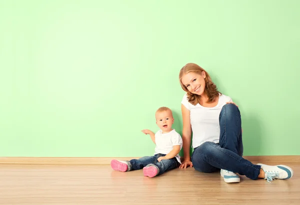 Happy family of mother and child sitting on the floor in an empt — Stock Photo, Image