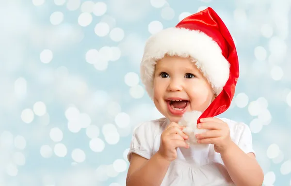 Beautiful funny baby in a Christmas hat on blue — Stock Photo, Image