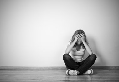 Kız bir depresyon duvarın yanında yerde oturuyor.
