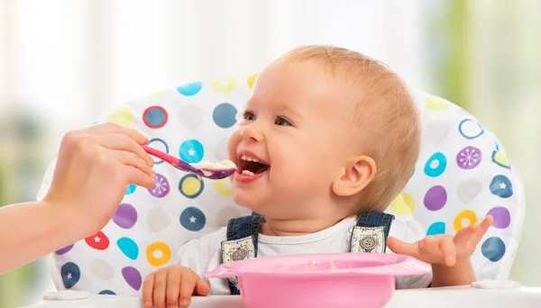 Mãe feliz alimenta bebê engraçado da colher — Fotografia de Stock