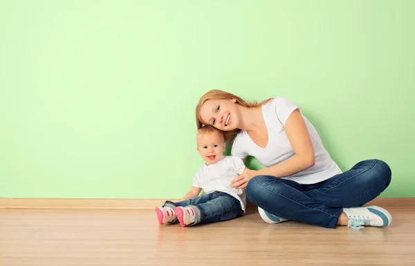 Happy family of mother and child sitting on the floor in an empt — Stock Photo, Image