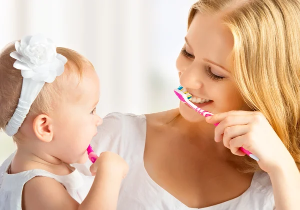 Moeder en dochter baby meisje samen hun tanden poetsen Stockafbeelding