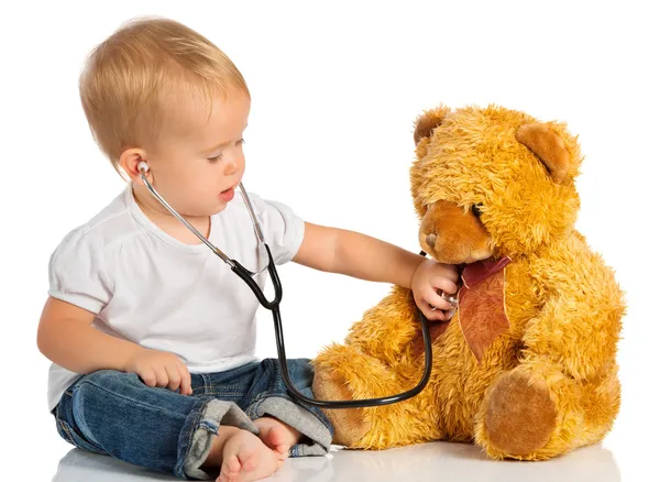 Bebê joga no médico brinquedo urso e estetoscópio — Fotografia de Stock