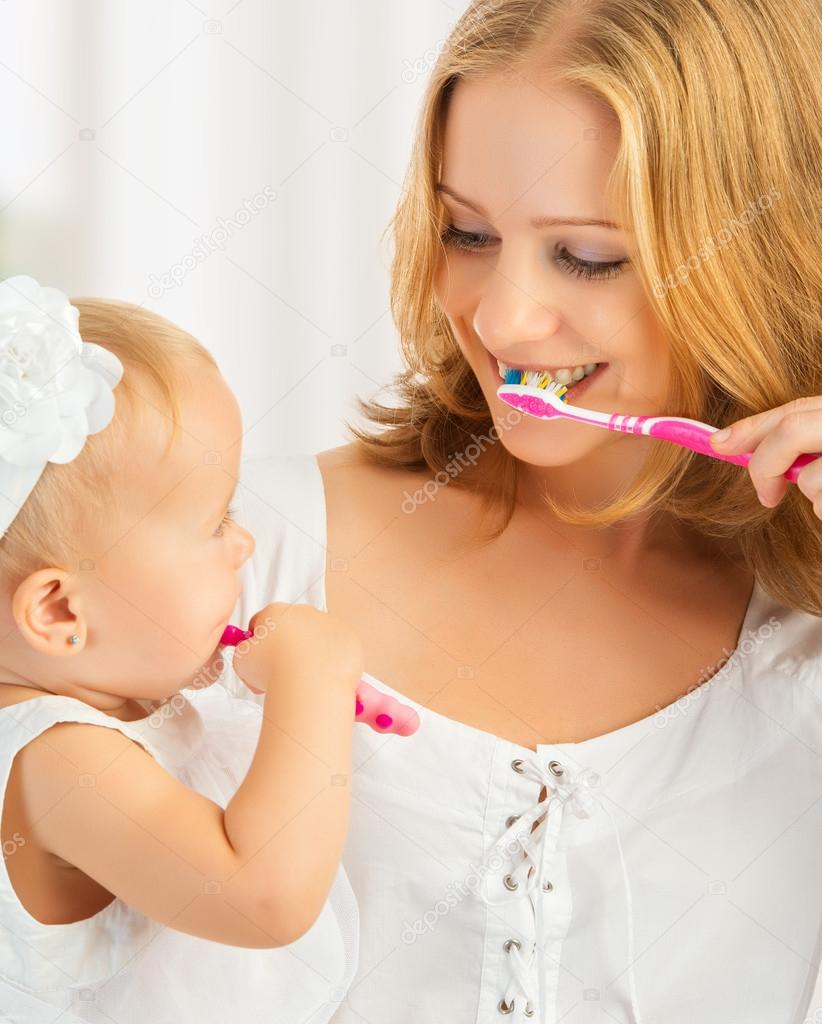 mother and daughter baby girl brushing their teeth together