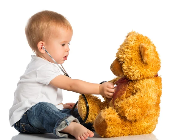 Baby plays in doctor toy bear and stethoscope — Stock Photo, Image