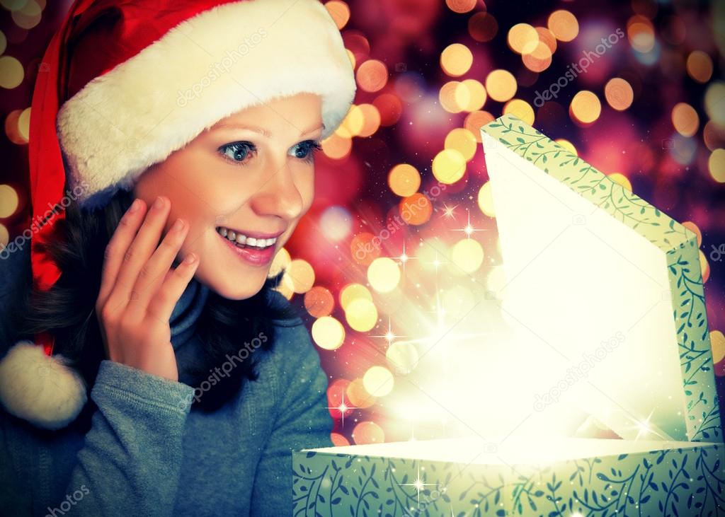 happy woman in a Christmas cap opens the magic box