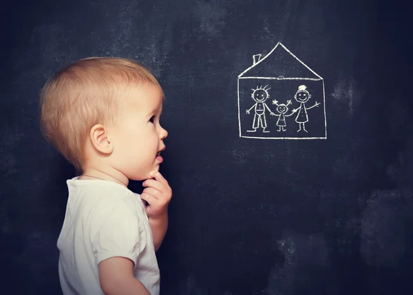 Concept baby looks at board, which is drawn family and home — Stock Photo, Image