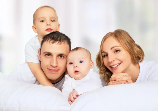 Família feliz de pai, mãe e filhos na cama branca — Fotografia de Stock