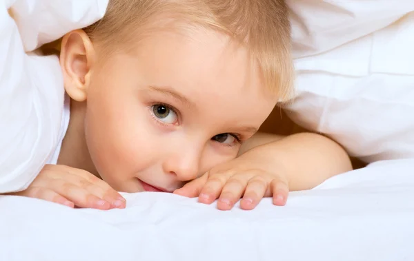 Gyermek kisfiú az ágyban fekve, takaró alatt — Stock Fotó