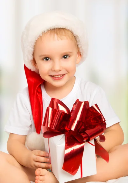 Little cute child boy in a Christmas hat with a gift — Stock Photo, Image