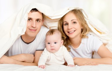 battaniyenin altına yatakta mutlu bir aile