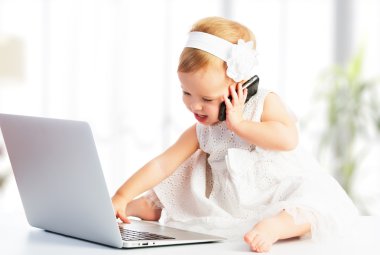 Bilgisayar laptop, cep telefonu ile kız bebek