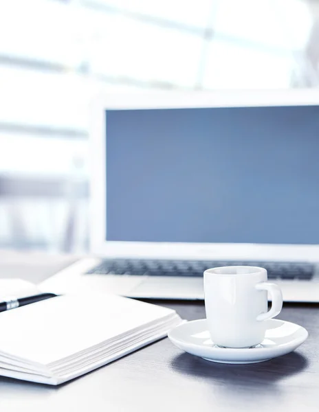 Scrivania con una tazza di caffè computer portatile, notebook, penna — Foto Stock