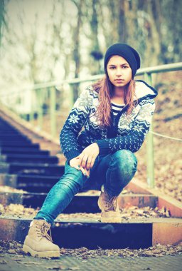 Yalnız kız genç merdiven ve hüzünlü sonbahar üzerinde oturan şapkalı