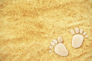 Yaz aylarında kumsalda sarı kum üzerinde taş ayak izleri