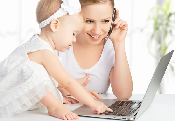 Mère avec bébé fille travaille avec un ordinateur et un téléphone — Photo