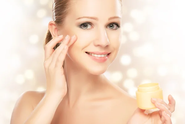 Giovane bella donna utilizzando una crema per il viso — Foto Stock