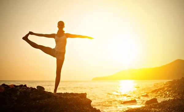 Vrouw doet yoga op het strand bij zonsondergang — Stockfoto