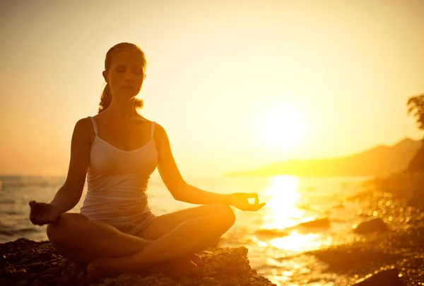 Mulher meditando em lótus posar na praia ao pôr do sol — Fotografia de Stock