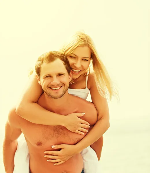 Happy family couple in love hugging and laughing on the beach — Stock Photo, Image