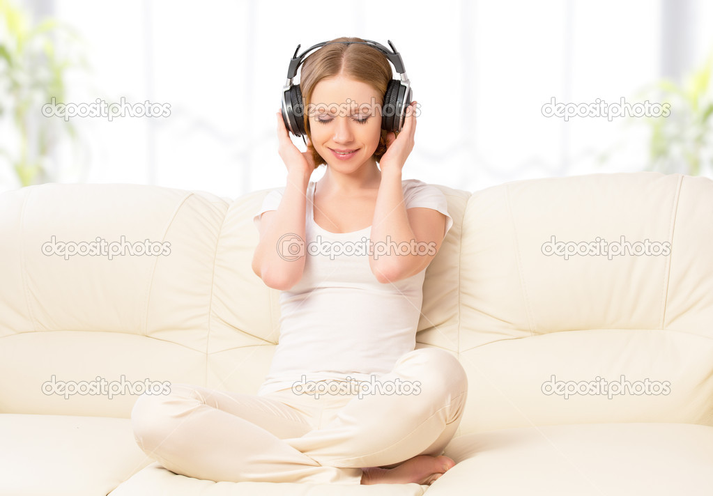 beautiful girl in headphones enjoying music at home on the couch