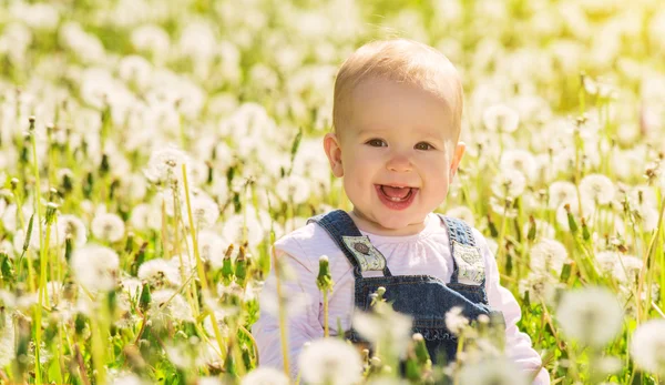 Gelukkig babymeisje op weide met witte bloemen op de aard — Stockfoto