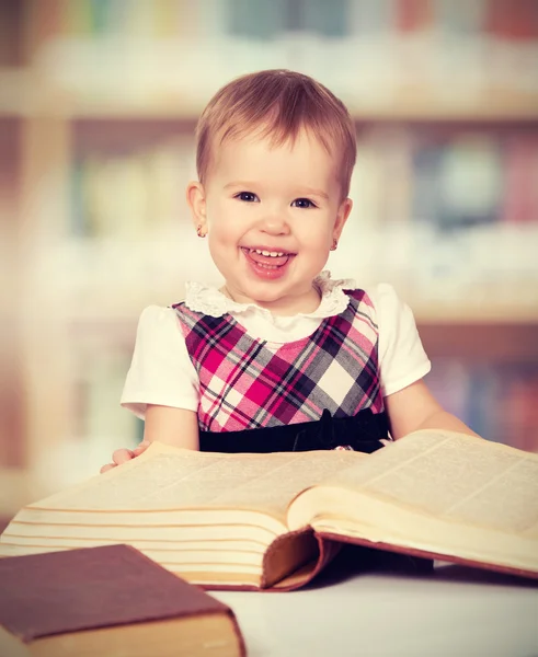 Boldog baba lány Olvasson egy könyvet a könyvtárban — Stock Fotó