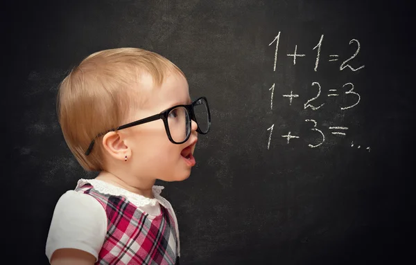 Funny girl pupil solves arithmetic examples on blackboard — Stock Photo, Image