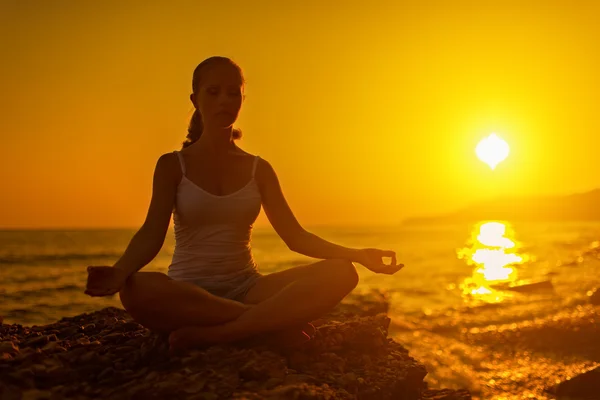 Kobieta medytacji w pozie Lotos na plaży o zachodzie słońca — Zdjęcie stockowe
