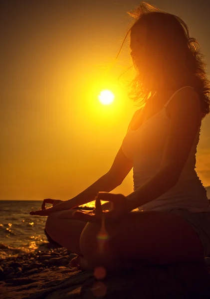 Frau meditiert in Lotus-Pose am Strand bei Sonnenuntergang — Stockfoto
