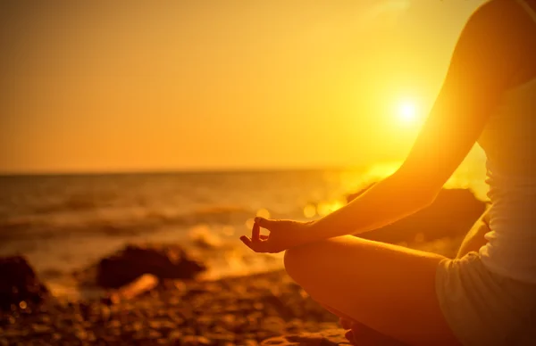 Hand av kvinna mediterar i en yogaställning på stranden vid solnedgången — Stockfoto