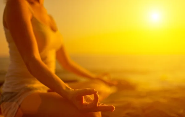 Mano de mujer meditando en una pose de yoga en la playa al atardecer — Foto de Stock