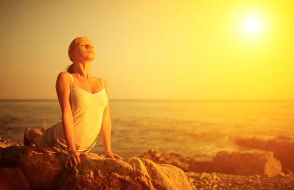 Gün batımında sahilde yoga yaparken kadın — Stok fotoğraf