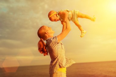 mutlu bir aile. Anne bebek gökyüzünde yukarı atar.
