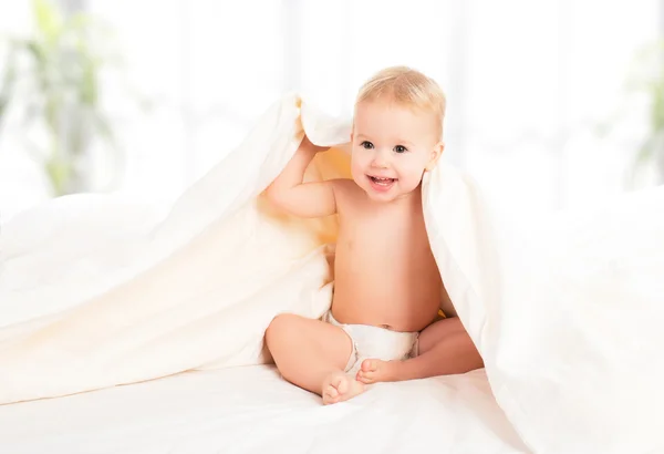 Happy baby under en filt skrattar — Stockfoto