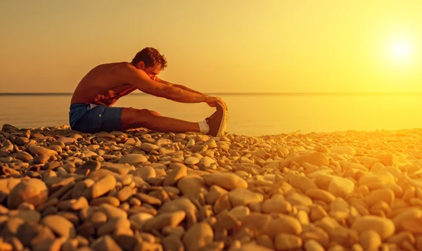 Спортсмен практикующий, занимающийся спортом и йогой на пляже на солнце — стоковое фото