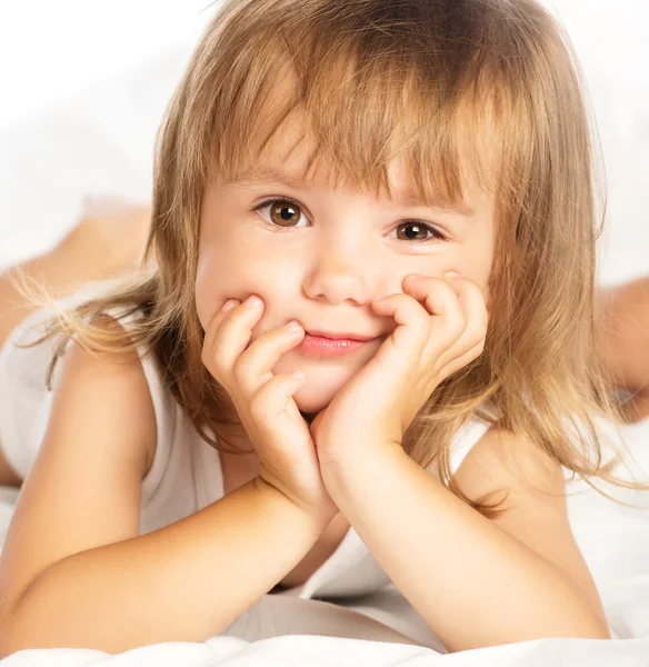 Pequena menina alegre sorridente feliz em uma cama isolada — Fotografia de Stock