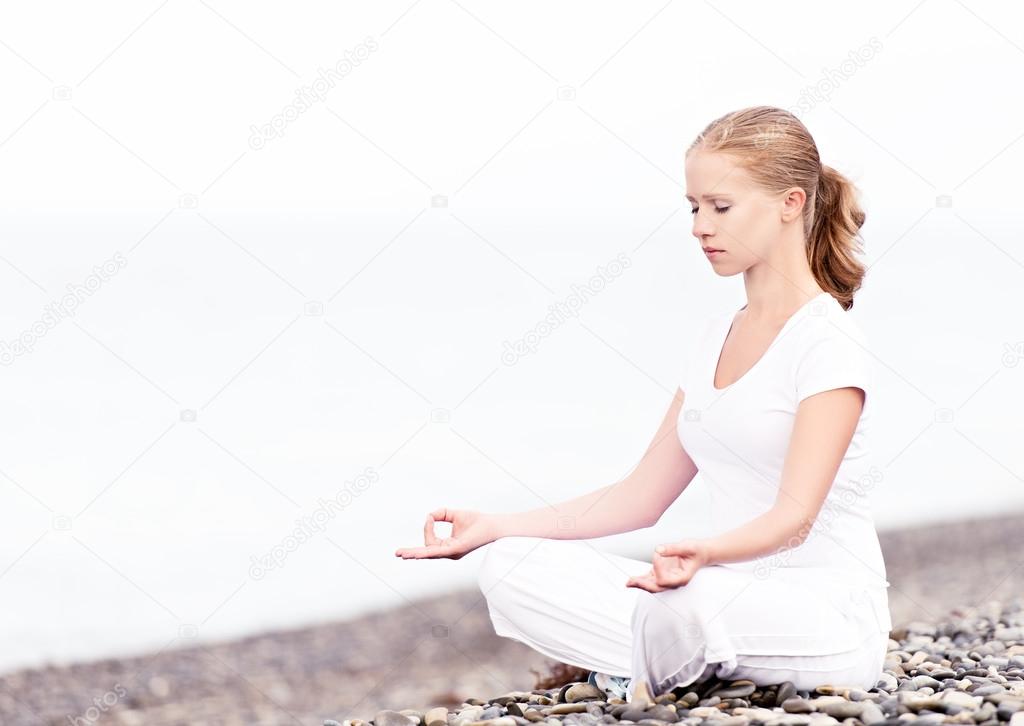 woman meditating in  lotus yoga on beach