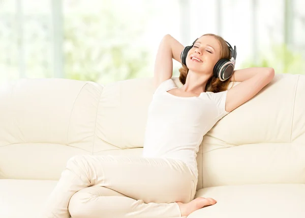 Vacker flicka i hörlurar njuter musik hemma — Stockfoto