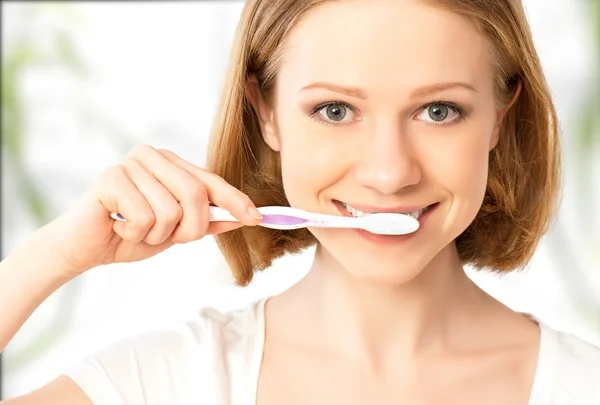 Mujer feliz cepillándose los dientes con un cepillo de dientes —  Fotos de Stock