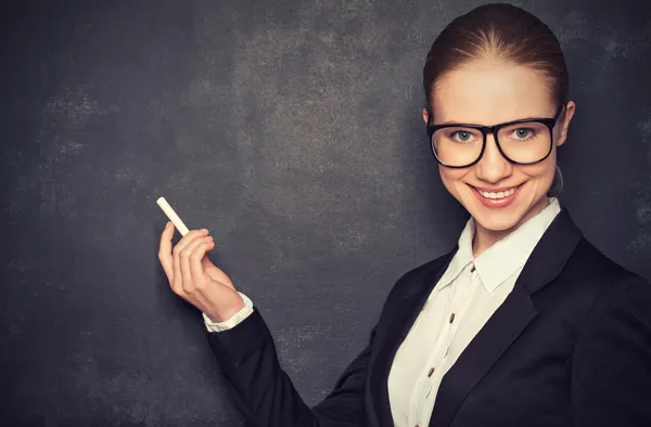 Business woman teacher with glasses and a suit with chalk   at a — Stock Photo, Image