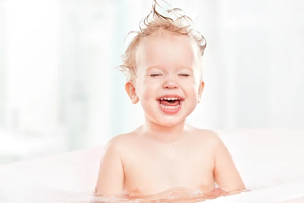 Счастливый смешной ребенок смеется и купается в ванне — стоковое фото